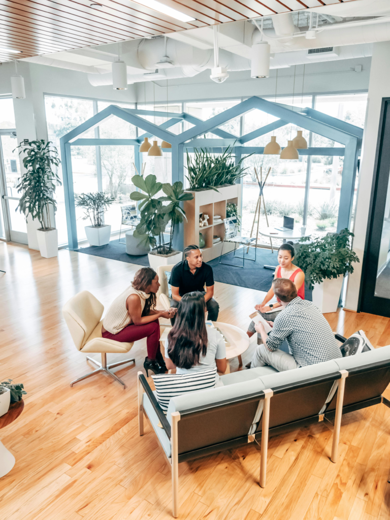 A diverse team in a modern office collaborating around a small table.